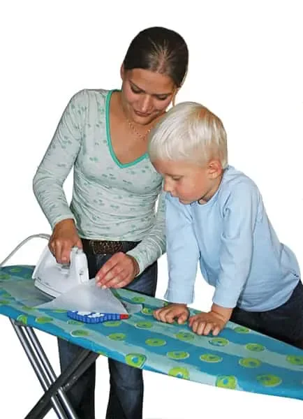 An adult using a household iron over protective paper while a child watches